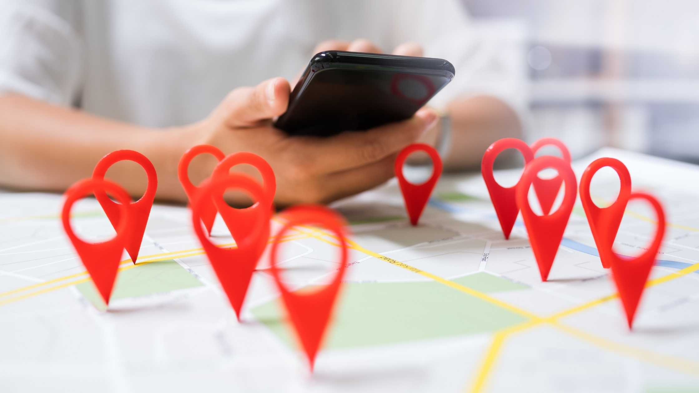 Graphic of a mobile device search over a map with location pins.