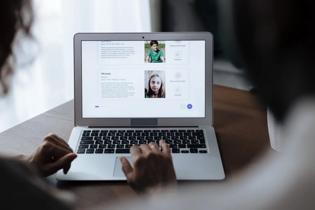 Unrecognizable Couple Looking at Laptop Screen Displaying Adoption Page