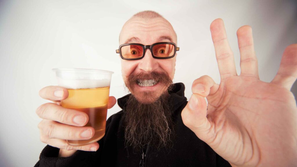 Photo of a man drinking a beer and giving it a thumbs up.